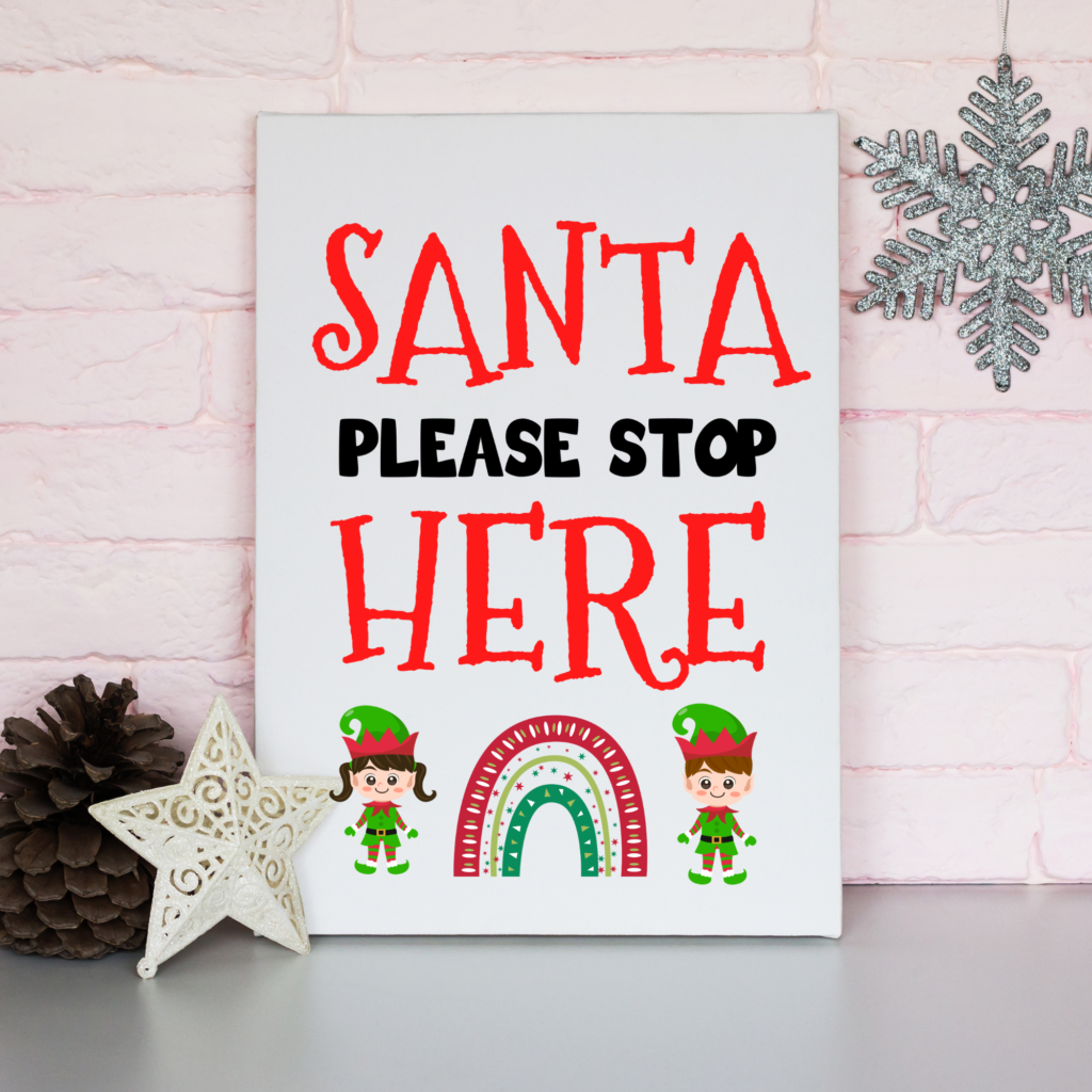 printable santa stop here against a wall with christmas decoractions