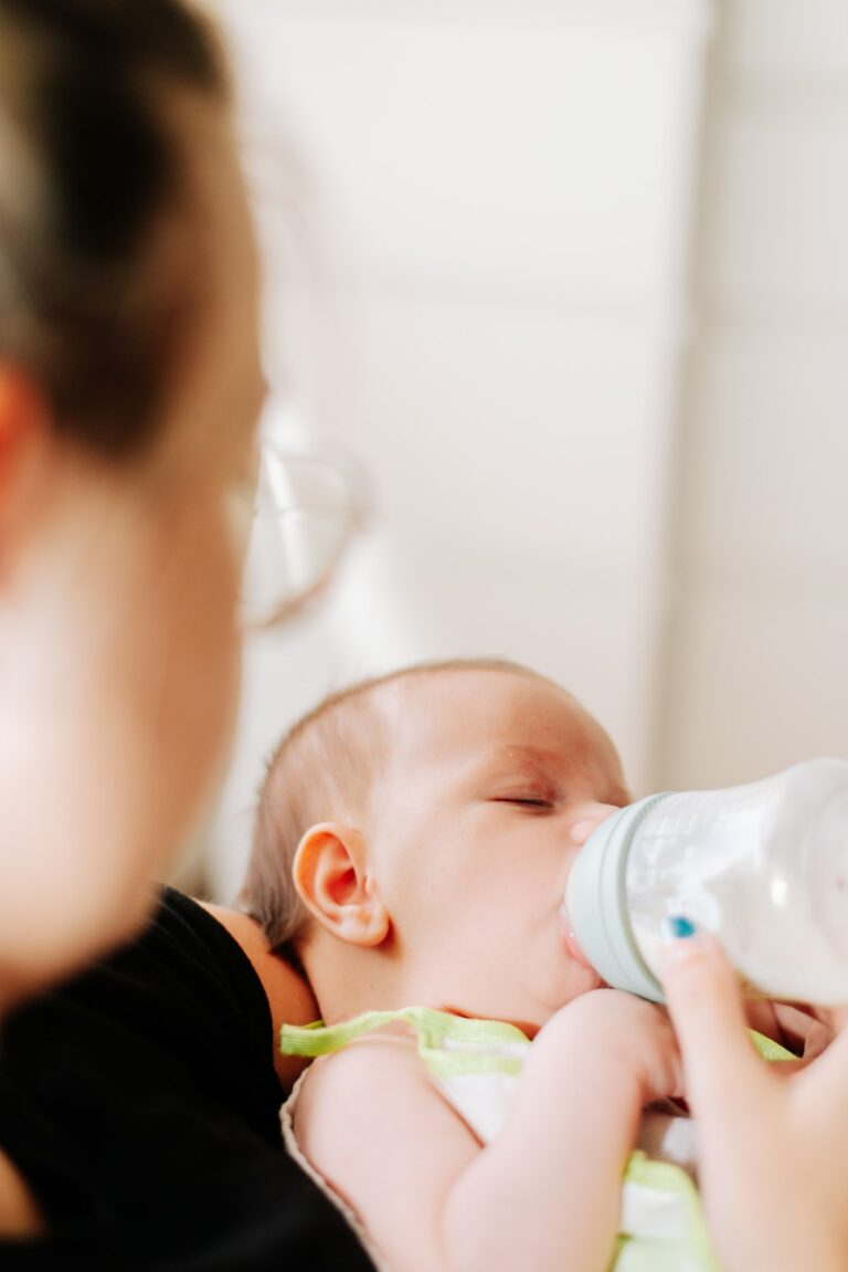 portrait of a newborn drinking from a feeding bottle How to Organize Your Day With a New Baby