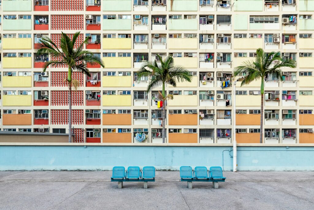Some benches in front of colorful facades of public housing complexes in Hong Kong - Moving to Hong Kong: A Relocation Guide for Expat Families